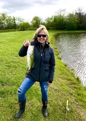 Tari Garner holding a fish, demonstrating outdoor fishing activities for students