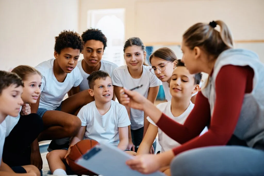 Students actively listening to a physical education teacher during an outdoor class